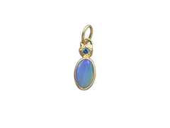 14K and sterling silver backing pendant with a blue oval boulder opal and a blue Montana sapphire set at the top in a star shape. On white background.