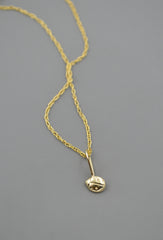 14k gold ladybug pendant on a chain on a gray background
