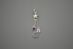 Silver charm featuring a small silver star with 3 separate chain pieces hanging from the bottom. Each has a different gemstone at the end. Purple amethyst, blue chalcedony and berry colored rhodolite garnet.