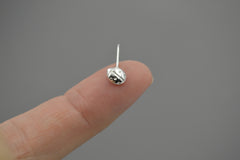 sterling silver ladybug pendant laying on a fingertip to show size