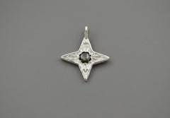 Silver Compass Star Pendant with textured surface and arrows. In the center is a black star sapphire. The "star" appears in direct sunlight.